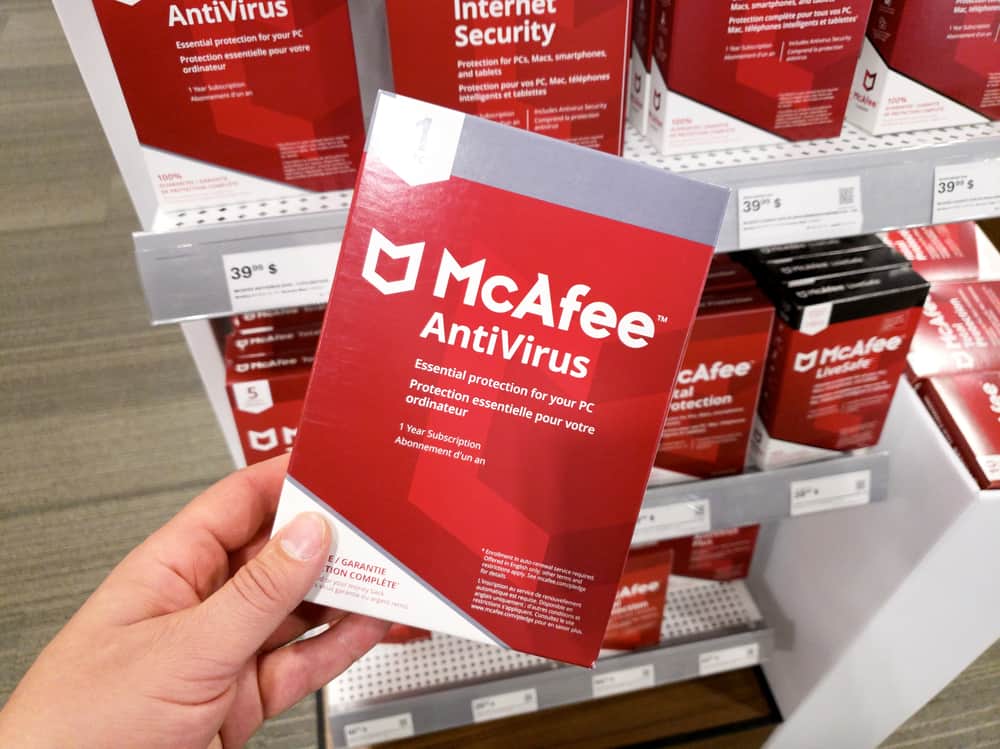 Рука тримає коробку McAfee Antivirus з ліцензією та програмою