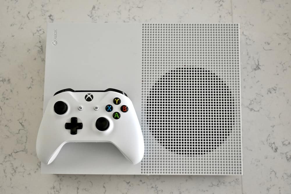 Біла консоль і контролер Xbox One S на мармуровій поверхні каррера.