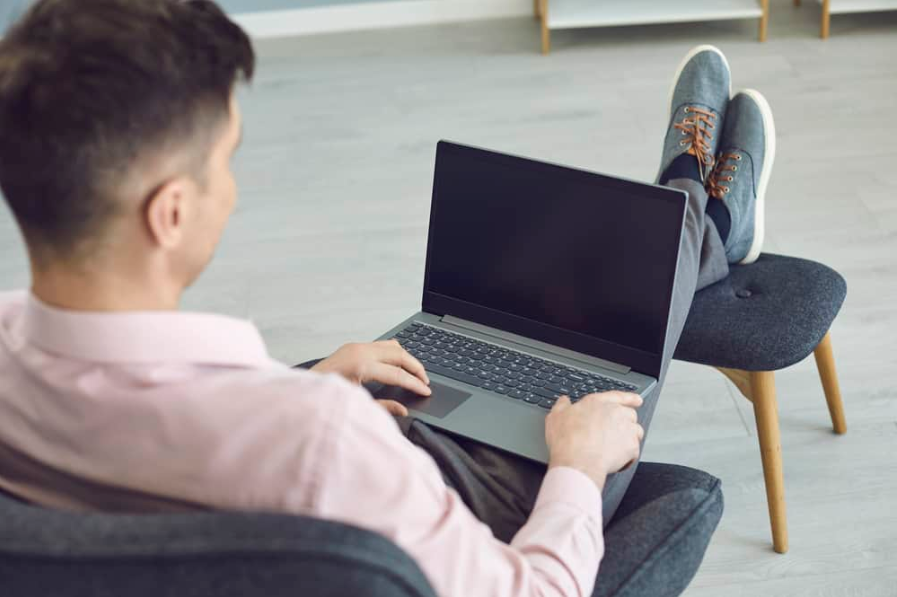 Задній вид анонімного чоловіка за допомогою онлайн-ноутбука вдома.