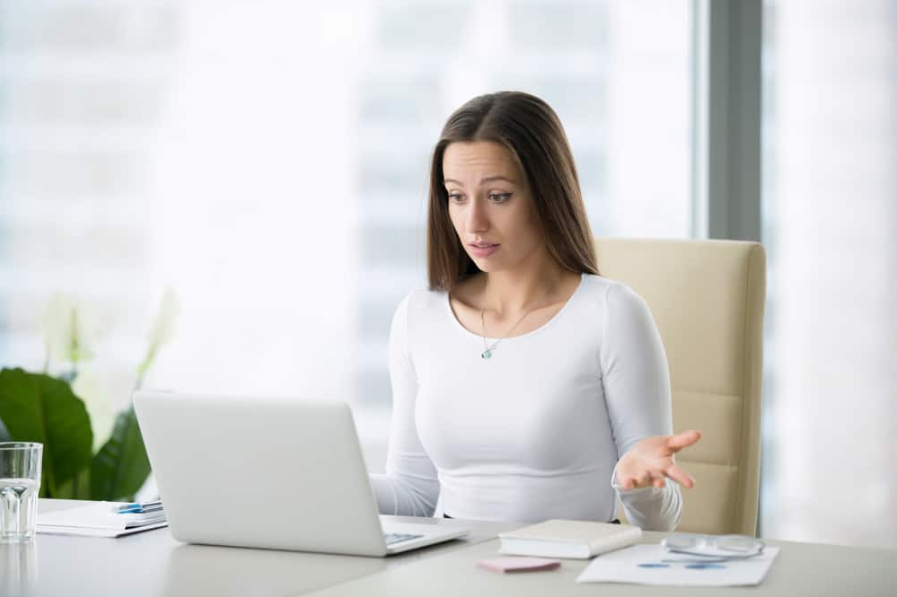 бізнес-леді за сучасним офісним столом з ноутбуком спантеличений