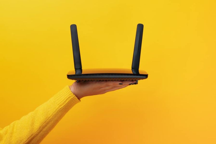 чорний Wi-Fi маршрутизатор на жіночій руці на жовтому фоні