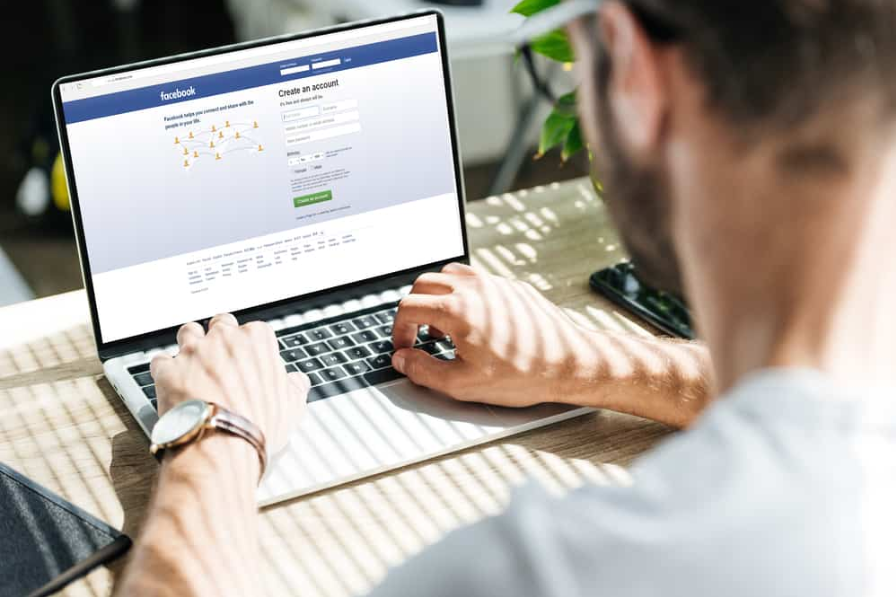 Частковий вид людини за допомогою ноутбука з веб-сайтом facebook на екрані