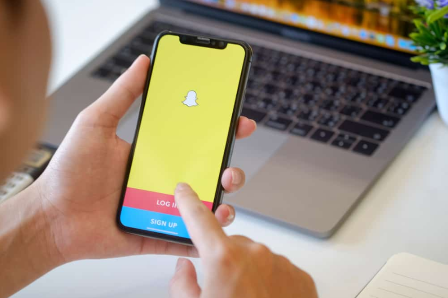 Чоловік тримає iPhone X із службою соціальної мережі Snapchat на екрані