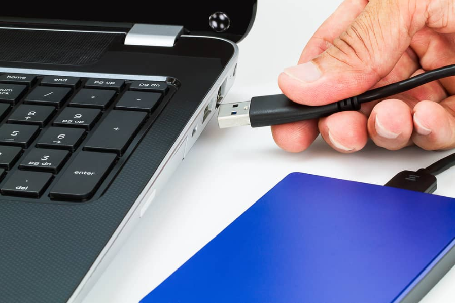 Рука підключення кабелю usb зовнішнього жорсткого диска до ноутбука на білому столі