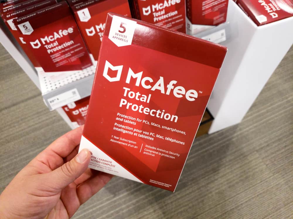 рука, що тримає коробку McAfee Total Protection з ліцензією та програмою