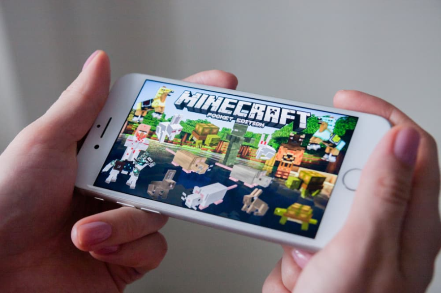 Руки тримають смартфон із грою Minecraft Pocket Edition на екрані, ілюстративна редакційна стаття
