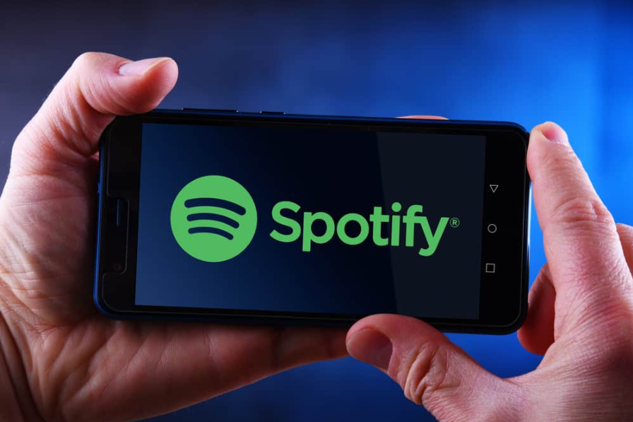 Руки тримають смартфон із логотипом Spotify