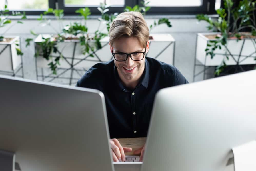 Щасливі програміст в окулярах за допомогою комп'ютерів в офісі