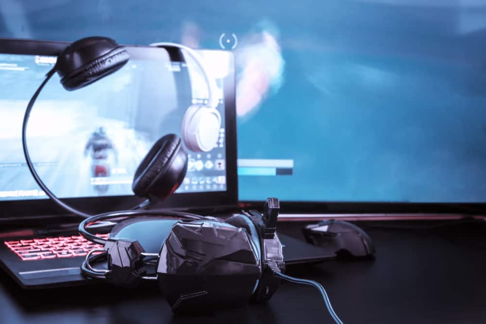 Ігровий комп'ютер, ноутбук, клавіатура, навушники та гарнітура для відеоігор на темному тлі