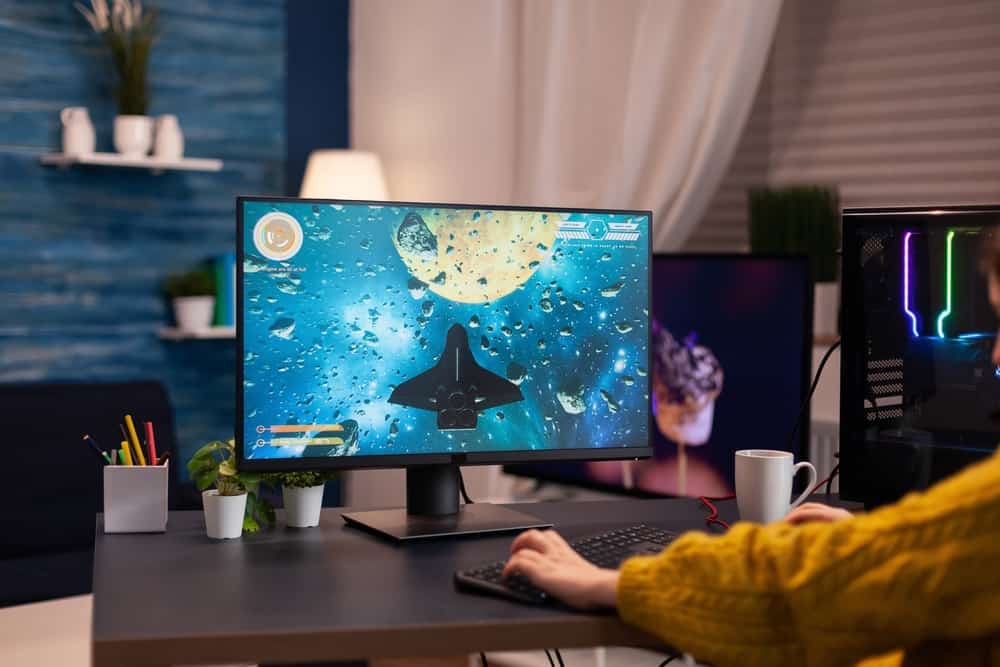 Крупним планом жінки-гравця, яка грає у відеоігри космічний шутер під час онлайн-чемпіонату, використовуючи потужний комп’ютер RGB у потоковій студії