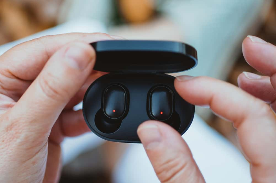 крупний план жінки, яка дістає бездротовий навушник із зарядної коробки