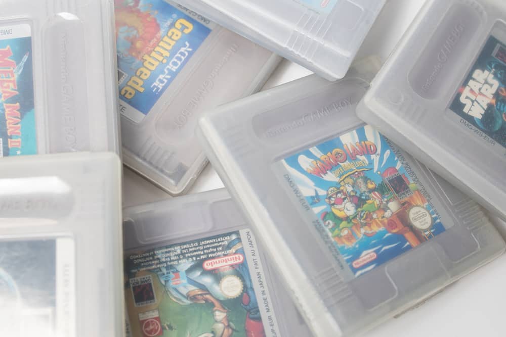 купа старовинних картриджів для комп’ютерних ігор на білому фоні.