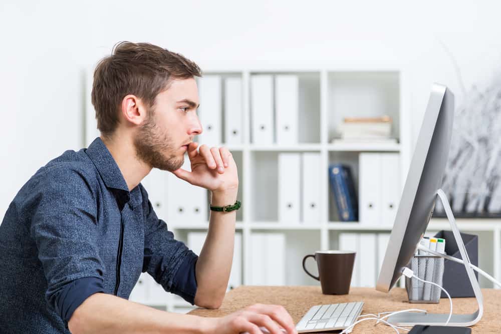 Чоловік дивиться на екран комп'ютера і важко думає