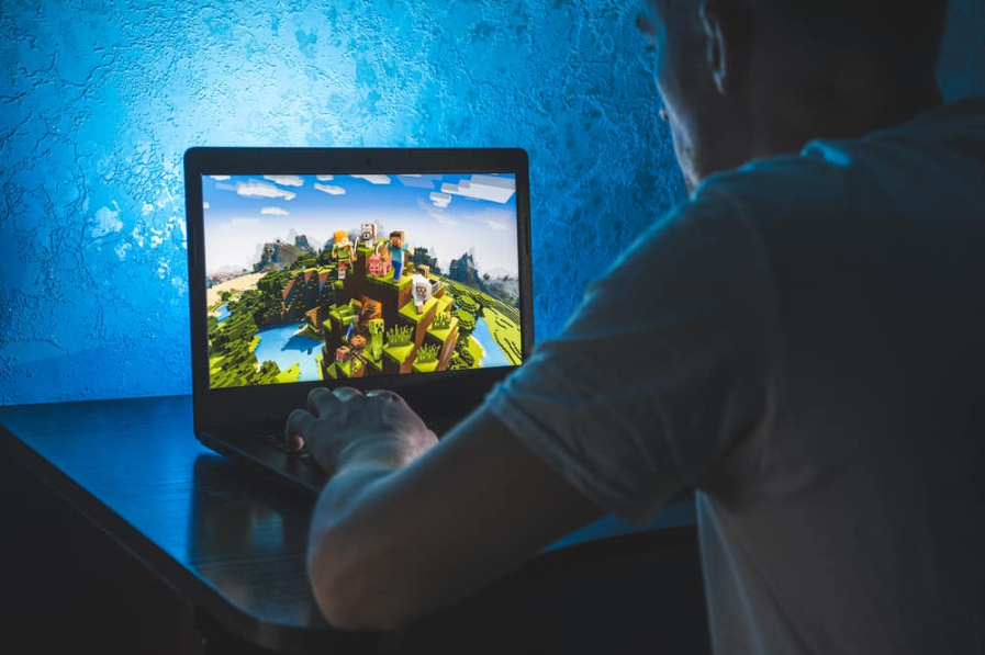 Людина, яка грає у відеогру Minecraft на комп’ютері