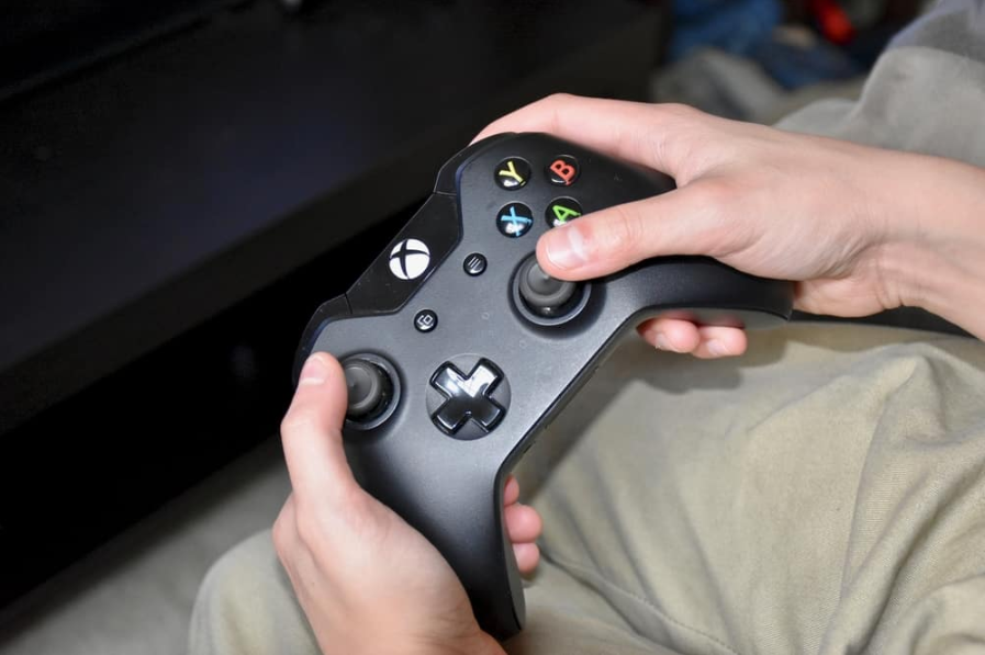 Людина, яка використовує контролер Xbox One, щоб грати в ігри на Xbox.