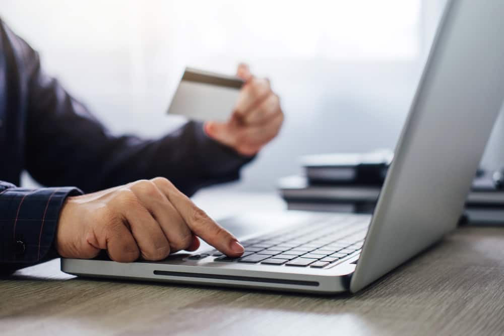 Чоловік набирає ноутбук для онлайн-покупок і оплати кредитною карткою