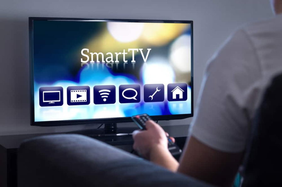 Чоловік дивиться Smart TV. Вибір фільму або серіалу з меню. Людина, що тримає пульт дистанційного керування. Інтерфейс користувача на екрані телевізора.