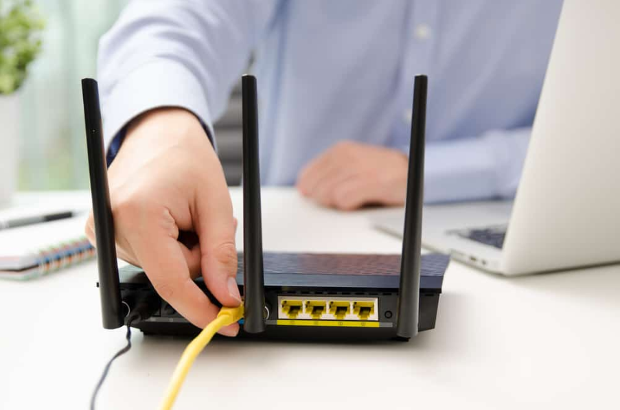 Чоловік підключає кабель Ethernet до маршрутизатора.