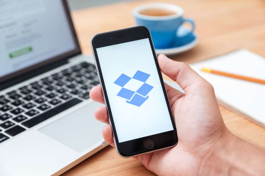 Чоловік тримає iphone 6 і демонструє додаток Dropbox