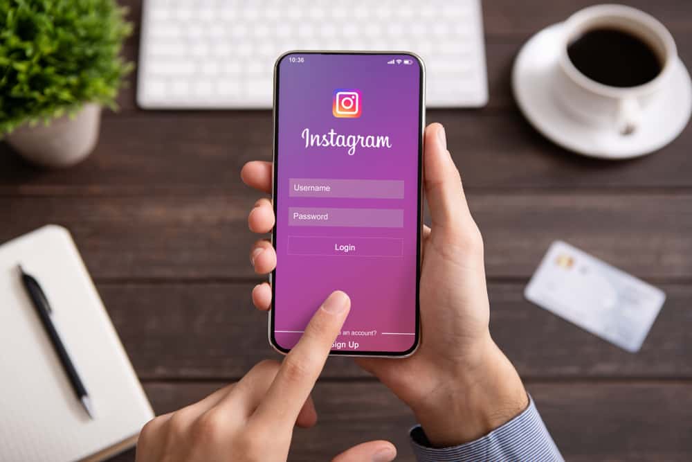 Чоловік тримає iPhone X Max із додатком соціальної мережі Instagram на екрані.