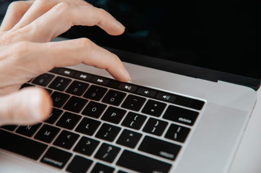 чоловік вимикає звук на своєму ноутбуці