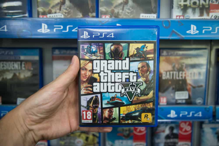 Чоловік тримає в магазині відеогру Grand Theft Auto 5 на консолі Sony Playstation 4