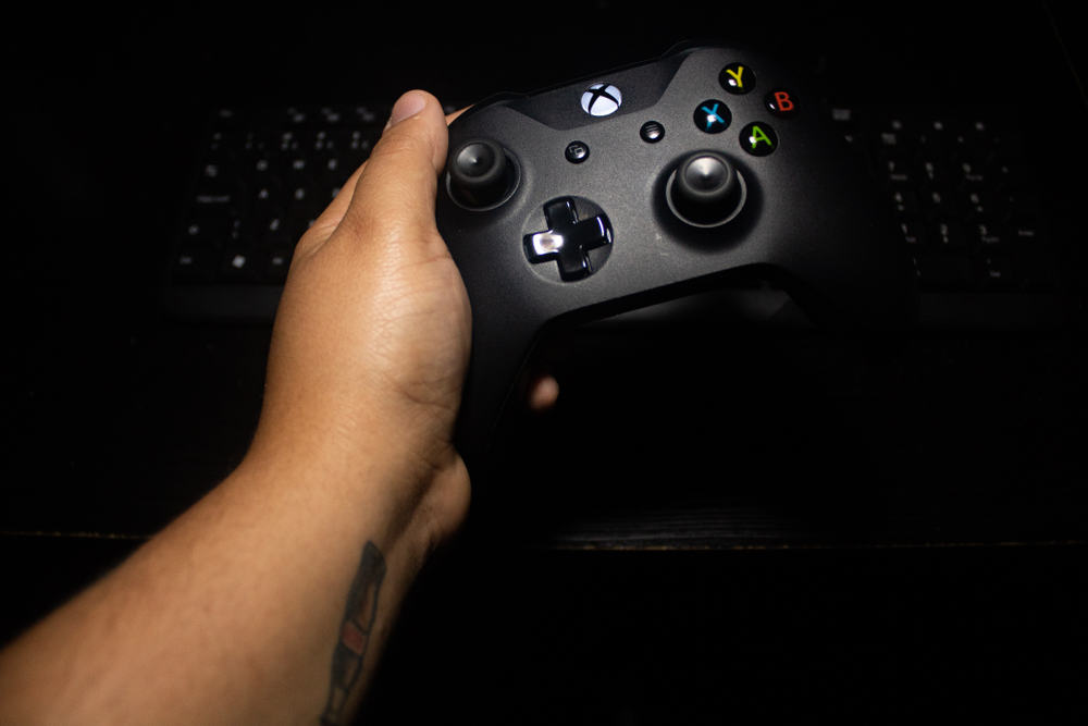 чоловік грає в xbox за допомогою керування та клавіатури