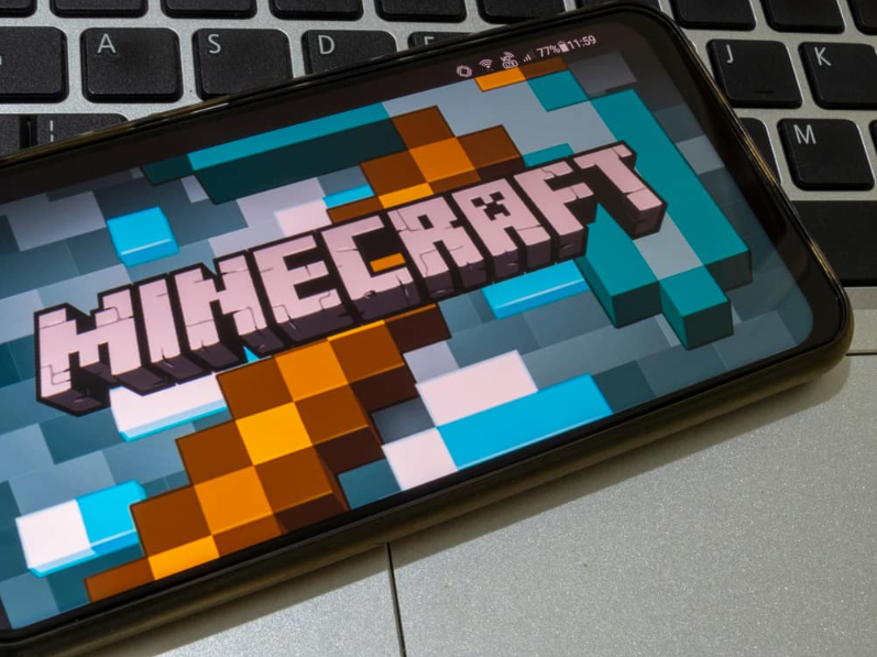 Minecraft. мобільний телефон на клавіатурі ноутбука з екраном гри Minecraft