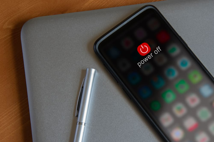 Мобільний пристрій вимикається, лежить на ноутбуці