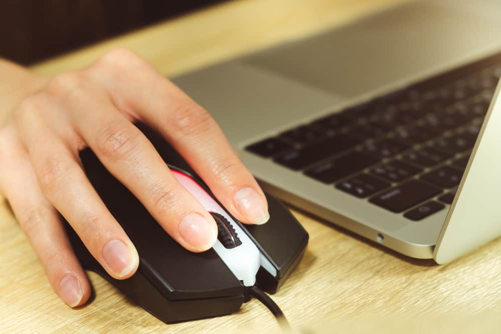 молода жінка, блогер, яка працює за ноутбуком вдома, крупним планом руки на миші