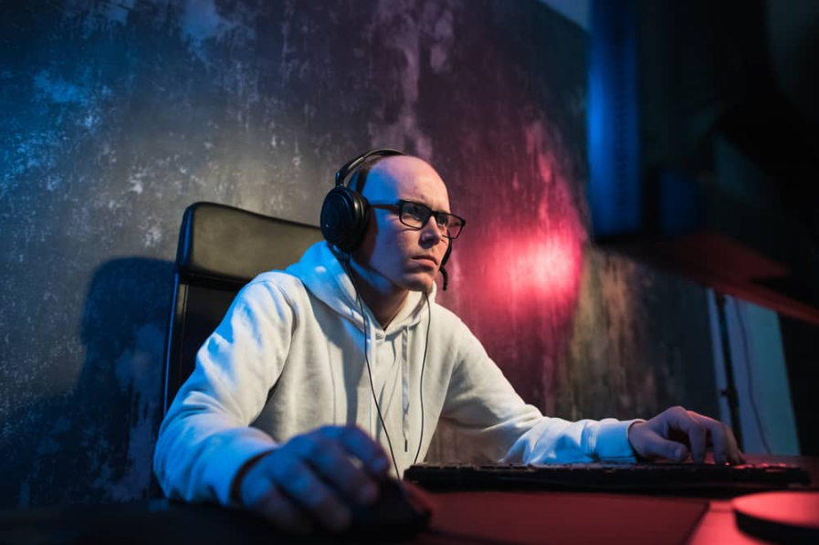 Портрет зосередженого молодого чоловіка в окулярах, ігровий комп'ютер