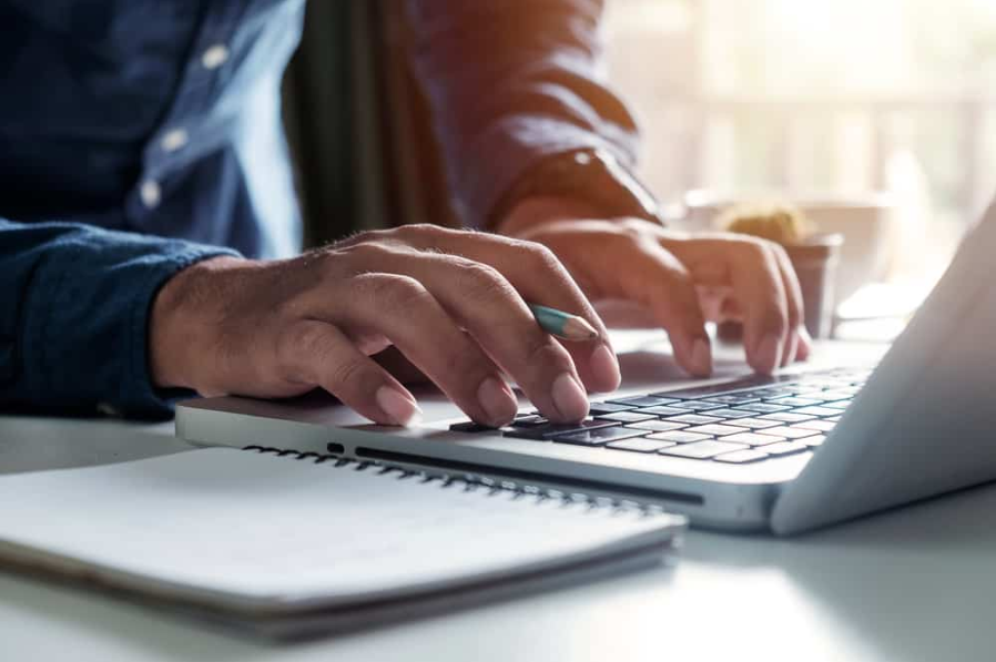 руки друкують на клавіатурі ноутбука