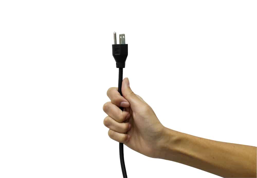 Рука тримає знімний шнур від розетки