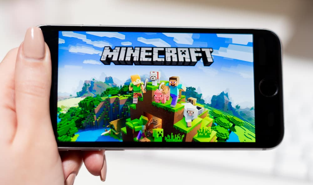Руки тримають смартфон із грою Minecraft на екрані