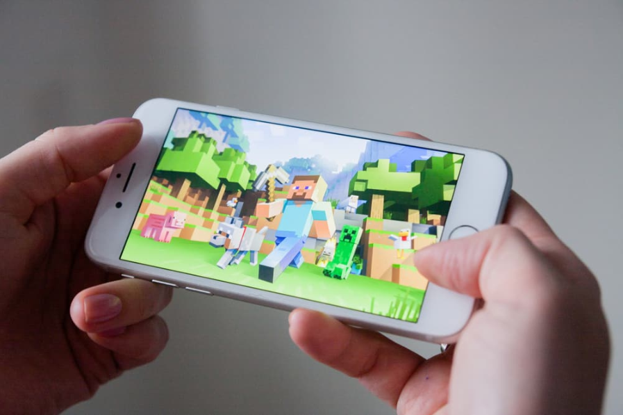 Руки тримають смартфон із грою Minecraft Pocket Edition на екрані