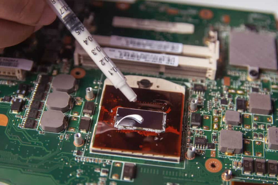 Технік наносить термопасту шприцом на процесор