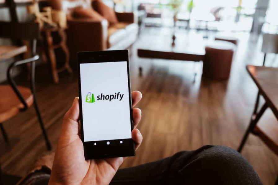 Телефон із додатком Shopify на екрані в кафе
