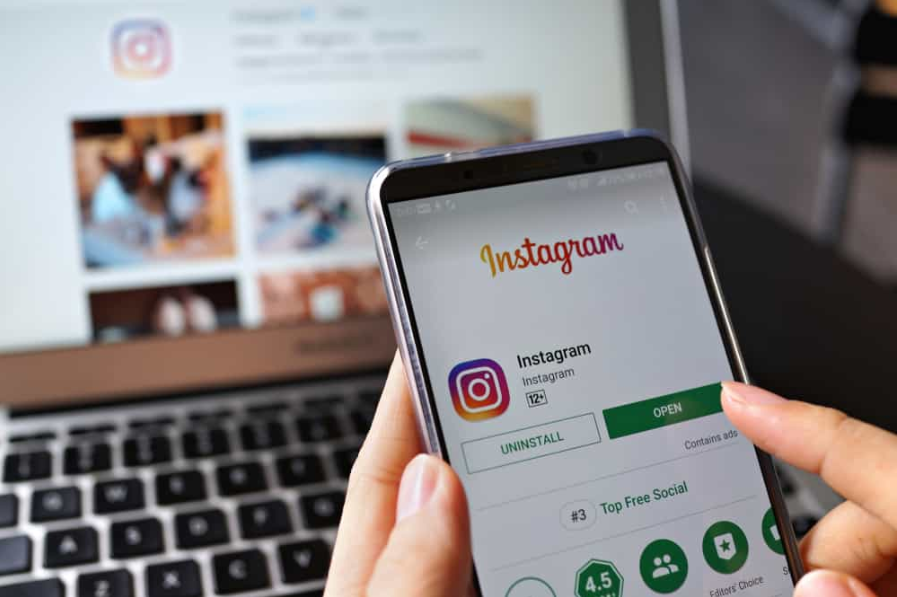 тримає на екрані смартфон із додатком соціальної інтернет-служби Instagram