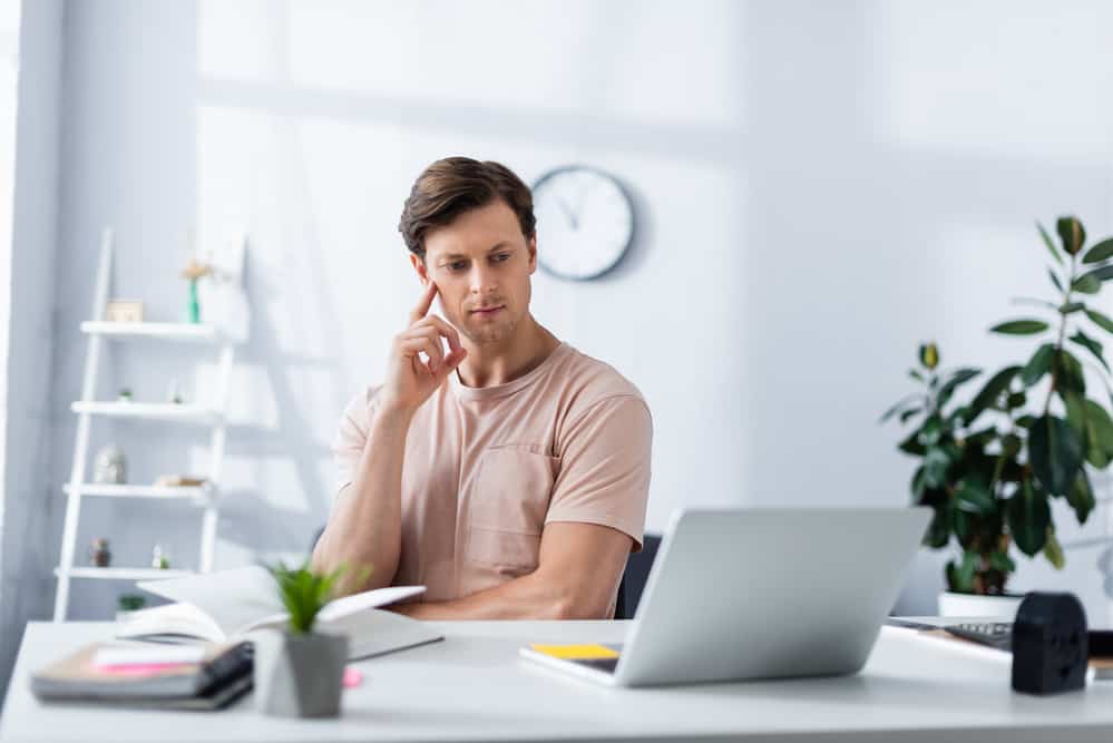 Вибірковий фокус вдумливий чоловік дивиться на ноутбук під час роботи і мислення