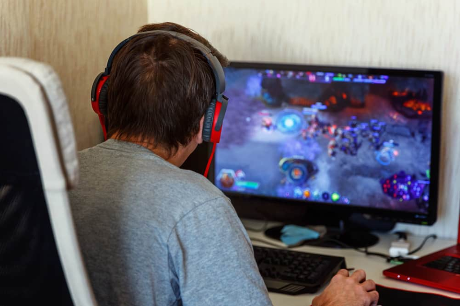 Задній вид зосередженого молодого гравця в навушниках