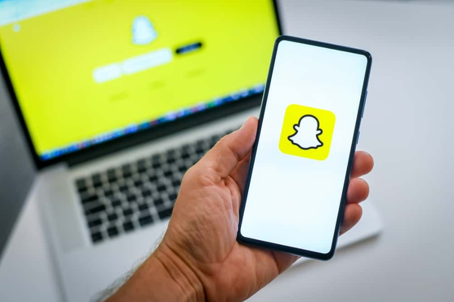 Крупним планом вид руки зі смартфоном і логотипом Snapchat на дисплеї