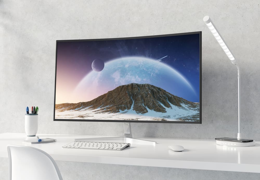 Вигнутий монітор на білому робочому столі та бетоні