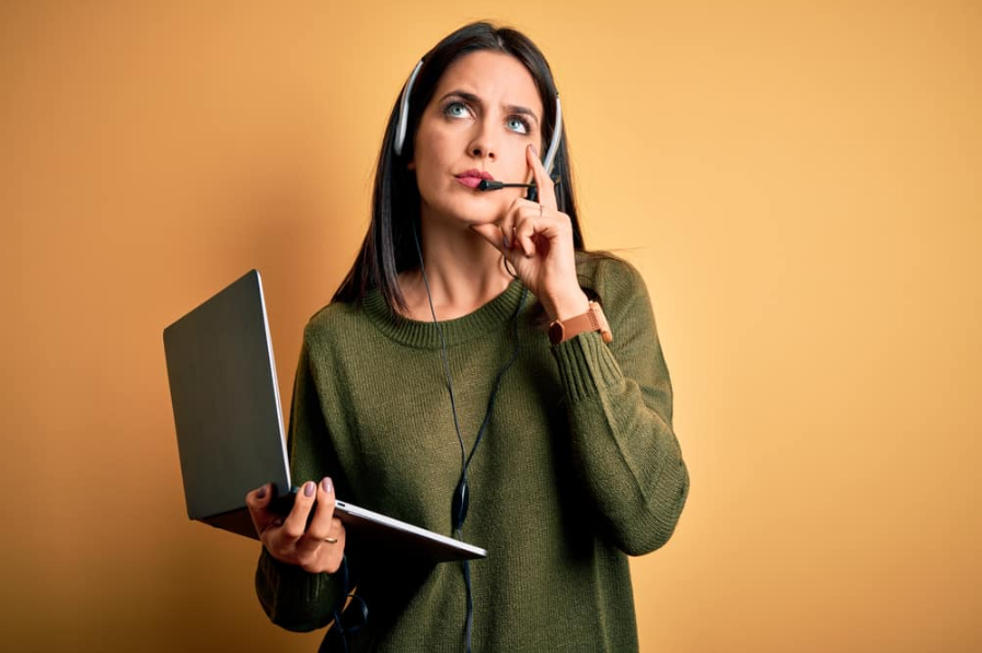 за допомогою комп'ютера ноутбук і гарнітура серйозне обличчя, думаючи про питання