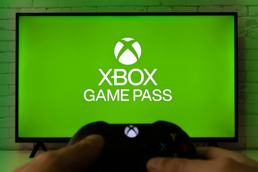 Xbox Game Pass на екрані телевізора з контролером Xbox у руках людини