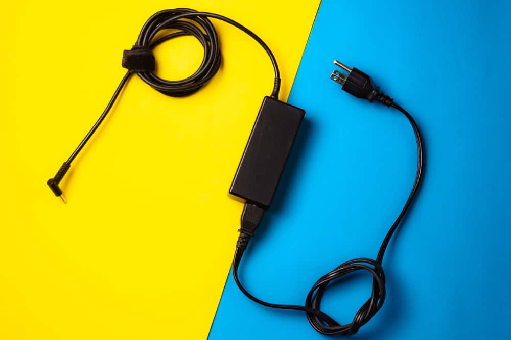 Зарядний пристрій для ноутбука над синьо-жовтим фоном