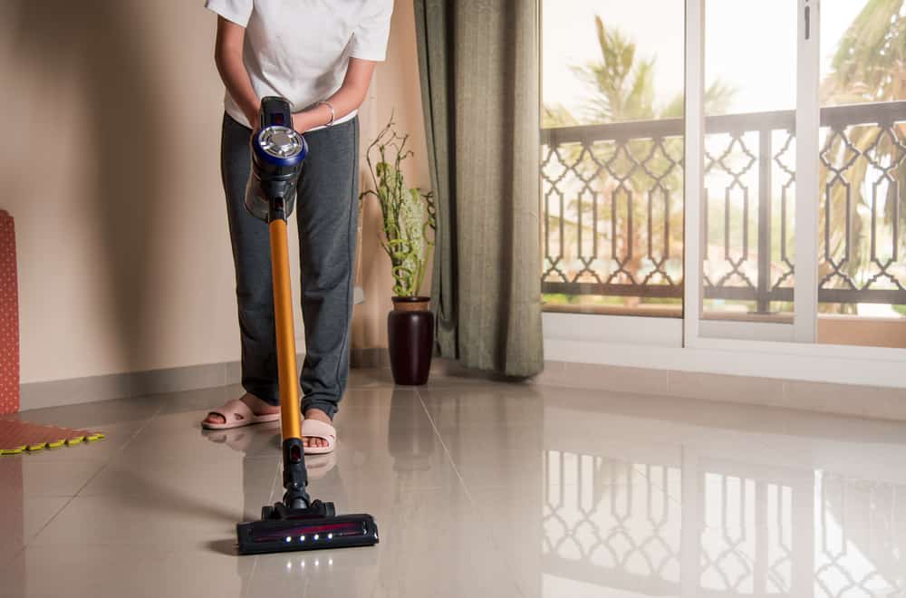 Жінка пилососить підлогу у вітальні