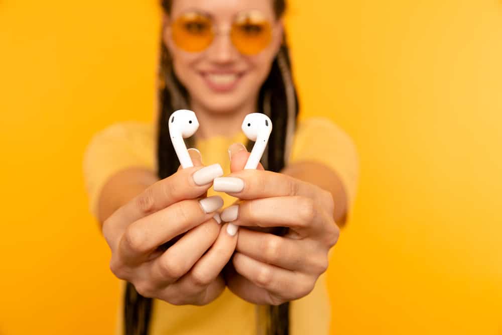 жінка показує airpods крупним планом