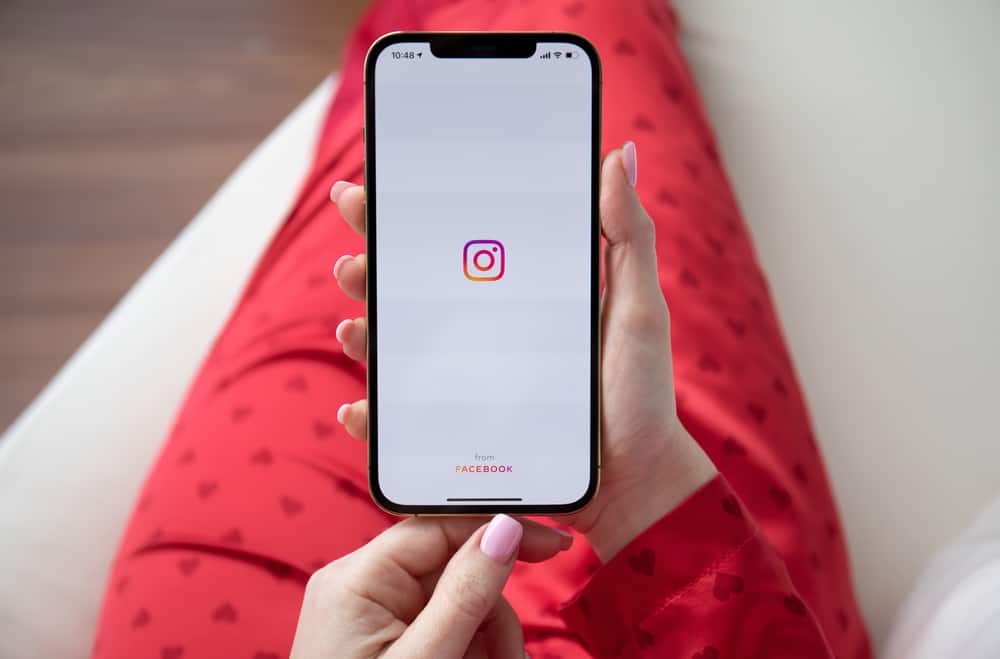 Жінка тримає за руку iPhone 12 Pro Max Gold із службою соціальної мережі Instagram на екрані.