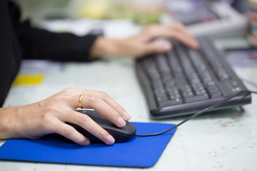 Жіноча рука, що тримає комп'ютерну мишу для офісної роботи