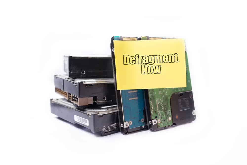 Жорсткий диск на ізольованих білому тлі з наліпкою з повідомленням defragent зараз